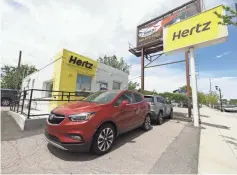  ?? DAVID ZALUBOWSKI/AP ?? Rental vehicles are parked outside a closed Hertz car rental office in south Denver in May.