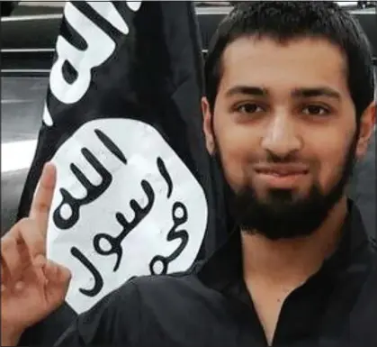  ??  ?? Doomed: Talha Asmal smiles for the camera in front of an IS flag shortly before the oil refinery attack