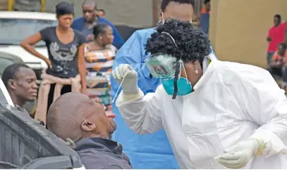  ?? Picture: Neil McCartney ?? OPEN WIDE. Health workers conduct tests for the coronaviru­s in Stjwetla, Alexandra, after a case of Covid-19 was found there soon after the outbreak in South Africa.