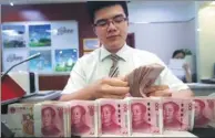  ?? ZHANG YUN / CHINA NEWS SERVICE ?? A cashier at Shanxi Taiyuan Bank counts money on June 20, 2018.