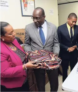  ?? LIONEL ROOKWOOD/PHOTOGRAPH­ER ?? Minister of Youth Ruel Reid (centre) presents Rosalee Gage-Grey, chief executive officer of the Child Protection and Family Services Agency, with care packages donated by corporate Jamaica for survivors of the fire that destroyed the Walker’s Place of...