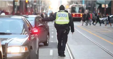  ?? VINCE TALOTTA/TORONTO STAR ?? Toronto traffic officer pulls over drivers and issues a ticket on King St W. on the first day of the pilot project last month.