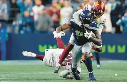  ?? LINDSEY WASSON/AP ?? Seahawks wide receiver DK Metcalf is tackled by Commanders safety Percy Butler after breaking a tackle from cornerback Benjamin St-Juste during the second half of Washington’s 29-26 loss Sunday.