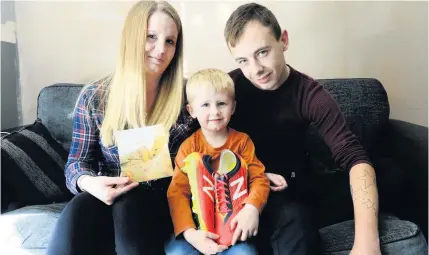  ??  ?? BRAVE: Archie Potts with mum Nikita Musselwhit­e, stepdad Stevan Sheppard and the signed boots sent to him by Lincoln City footballer Ellis Chapman.