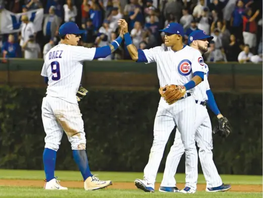  ?? DAVID BANKS/AP ?? Second baseman Javy Baez and shortstop Addison Russell celebrate the Cubs’ 3-0 win against the Brewers that put their division lead back at two games.