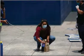  ?? (AP/Moises Castillo) ?? Deported Guatemalan Vanessa Diaz looks toward her family last month as she picks up the food they delivered to the site in Guatemala City where those who are returned from the U.S. are held in quarantine for two weeks.