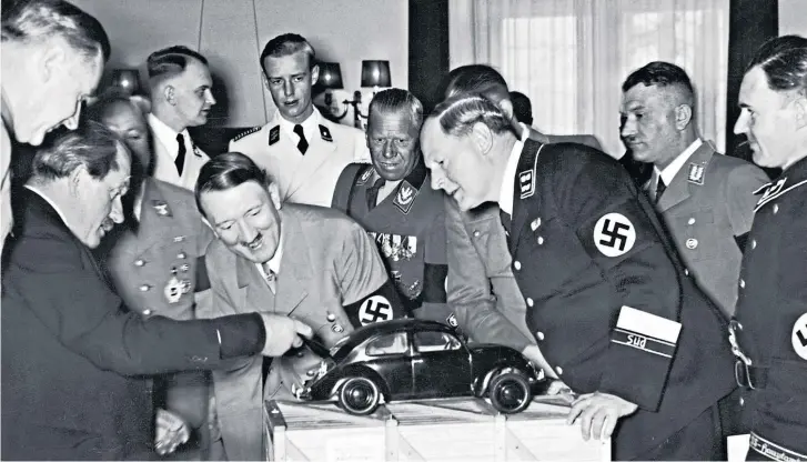  ?? ?? Up to their necks in the Nazi project: designer Ferdinand Porsche (left), pictured showing Hitler a model of the Volkswagen in 1938, filled his company Porsche with ex-SS officers after the war