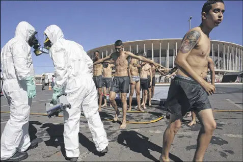  ?? ERALDO PERES / ASSOCIATED PRESS ?? A soldier dressed in a hazmat suit holds a machine that reads radiation levels during the practice of a decontamin­ation plan on Thursday outside the National Stadium in Brasilia, Brazil, which will host the 2016 Summer Olympics soccer matches. The...