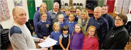  ??  ?? Tony McGuire Jones with parents and children of Ysgol Talwrn, Anglesey, who are concerned about the future of the school.