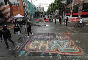  ?? Associated Press ?? ■ People walk past street art that reads "Welcome to CHAZ" inside what is being called the "Capitol Hill Autonomous Zone" on June 11 in Seattle.