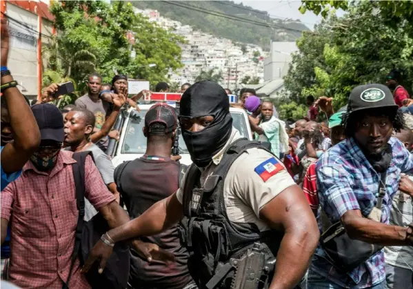  ?? AFP ?? La gente vitoreó cuando un vehículo de la Policía pasaba por la comisaría de Petionvill­e, donde permanecen presos varios hombres acusados de estar involucrad­os en el homicidio del presidente Jovenel Moise, en Puerto Príncipe.