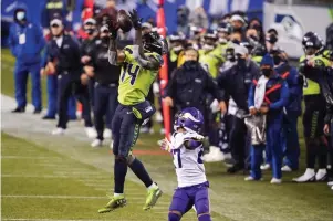  ?? AP Photo/Ted S. Warren ?? ■ Seattle Seahawks’ DK Metcalf (14) pulls in a long pass reception on the Seahawks' last series of an NFL football game as Minnesota Vikings’ Cameron Dantzler defends late in the second half Oct. 11 in Seattle. The Seahawks won, 27-26.