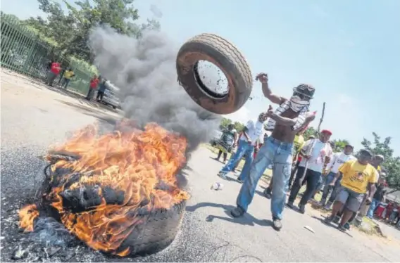  ?? Picture: Yeshiel Panchia ?? FUEL TO THE FIRE. A protester throws a tyre onto a burning pile outside Hoërskool Overvaal in Vereenigin­g yesterday. Members of the ANC and Economic Freedom Fighters protested outside the school.