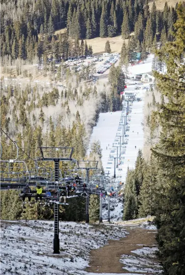  ?? LUIS SÁNCHEZ SATURNO/NEW MEXICAN FILE PHOTO ?? Bare ground is seen in December as skiers ride the quad chair at Ski Santa Fe to where there’s enough snow to ski.