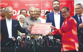  ??  ?? Mahathir and Muhyiddin (left) handing the PPBM membership card to Noor Azmi yesterday.