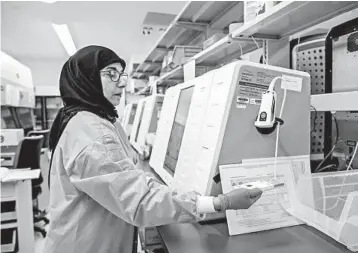  ?? JOHNNY MILANO/THE NEW YORK TIMES ?? A lab worker demonstrat­es what she has to do to process a coronaviru­s test Wednesday in Lake Success, New York.