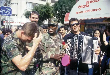  ?? (Alex Levac, IDF archive) ?? US SOLDIERS celebrate Purim and the Gulf War’s end on the streets of Tel Aviv, as children spray snow foam and Israelis play music.