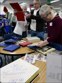  ?? ?? Linda Mccann, left, holds up a memory book showing their children as her husband, Bill Mccann, center, takes a photo Thursday during the 50th anniversar­y celebratio­n for Mary Blair Elementary School in Loveland. Sandy Bilstad, right, who taught at the school, also looks at photo albums. Bilstad’s husband was also a teacher at the school.