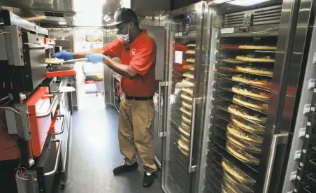  ?? Photos by Michael Macor / The Chronicle ?? Skylar Morris works inside the mobile kitchen where robotic pizza makers help prepare orders that will be handed off to drivers. The company has come under scrutiny for a recent investment from a Saudi-backed fund.