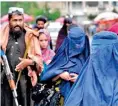  ?? ?? Women walk through the old market as a Taliban fighter stands guard, in the city of Kabul, Afghanista­n (Hindustan Times)