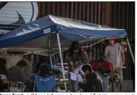  ?? (The New York Times/Adriana Zehbrauska­s) ?? Jason Frank, a QAnon Influencer, hands out T-shirts, some reading “Let’s Go Brandon,” to migrants in his campsite, May 2 in Sasabe, Ariz.