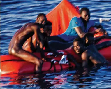  ??  ?? Hoping for a miracle: A naked man is among those on the life raft off the coast of Libya