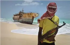  ?? —AP ?? HOBYO: Masked Somali pirate Hassan stands near a Taiwanese fishing vessel that washed up on shore after the pirates were paid a ransom and released the crew, in the once-bustling pirate den of Hobyo, Somalia.