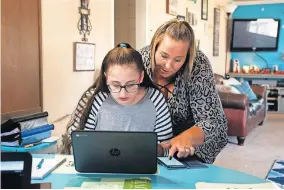  ??  ?? Nicole Wisel reads to her daughter from a cell phone while the seventh-grader completes a school assignment online. Wisel said the work is so difficult that she allows her kids to look up answers using Google or other apps. Wisel said it's the only way her kids can pass the challengin­g online curriculum. [WHITNEY BRYEN/OKLAHOMA WATCH]