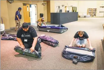  ?? ?? Volunteers, including Israel Cox and Avery Middleton (front), roll up air mattresses that are available for Ukrainian evacuees that stop there after crossing the border into the U.S.