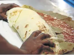  ?? Picture: JACKIE CLAUSEN ?? BIG JOB: Safe hands are needed to fold over the roti, which weighs in at nearly 4kg