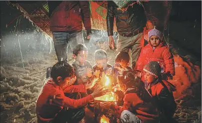  ?? MUHAMMED SAID / GETTY IMAGES ?? Refugee children gather around a fire at a camp in Idlib, Syria, during a harsh winter in January. Amid the bitter cold, many civilians were forced to burn their clothes in an effort to stay warm.