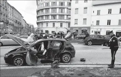  ?? REUTERS ?? Police examine the car of the suspected gunman who shot and injured six African migrants in Macerata, Italy, on Saturday, in what authoritie­s believe was a racially motivated attack.