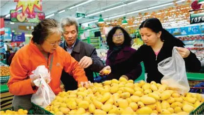 ??  ?? HANGZHOU: Customers select mangos at a supermarke­t in Hangzhou, east China’s Zhejiang province yesterday. Prices for goods at the factory gate in China jumped in March, the government said. — AFP