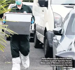  ?? NIALL CARSON ?? Police officers search a house in Newry, Co Down as part of Operation Venetic. Below: some of the luxury cars and other
items recovered in the raids