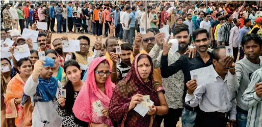  ?? PTI ?? Voters show their identity cards as they queue up to cast their vote at a polling station in Jabalpur, Madhya Pradesh, on Monday. —