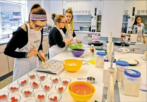  ??  ?? Kelsey Humlan makes meringue cookies and raspberry foam during a molecular gastronomy class in the Carlow University food lab.