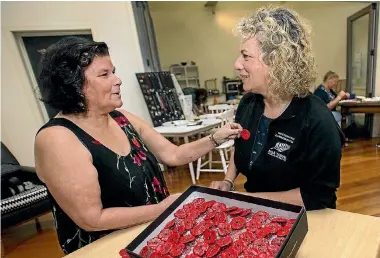  ?? PHOTOS: WARWICK SMITH/STUFF ?? Kathy Brereton presents her handcrafte­d poppies to New Zealand Defence Force senior communicat­ions adviser Emma Horsley so they can be taken to Anzac Day commemorat­ions overseas.