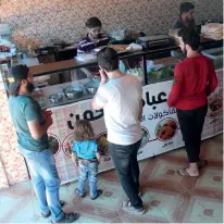  ?? Photos: CFP ?? Clockwise from right: Syrians stand in line at the Ibad al-Rahman’s Damascene Delicacies in Idlib on July 19. Syrian men eat at Damascene Delicacies. A Syrian man prepares food at Damascene Delicacies.