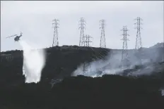  ?? JEFF CHIU/AP ?? In this Oct. 10, 2019, file photo, a helicopter drops water near power lines and electrical towers while working at a fire on San Bruno Mountain near Brisbane, Calif.