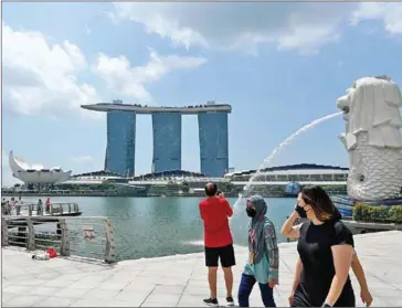  ?? AFP ?? People walk past the Merlion statue in Singapore on Thursday.