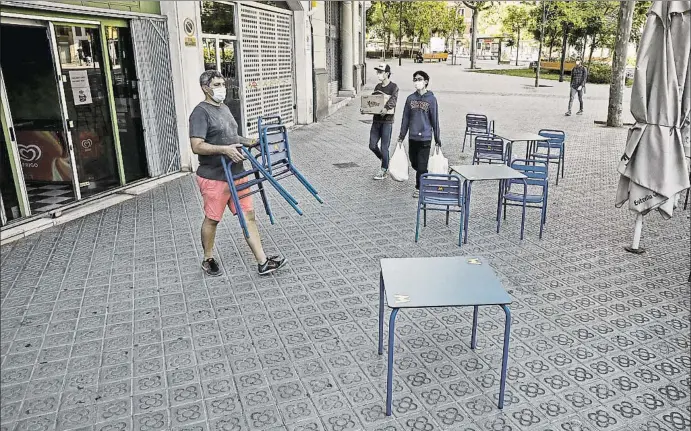  ?? ÀLEX GARCIA ?? El propietari­o de una cafetería de la plaza Tetuán de Barcelona se prepara para montar la terraza con la medición de distancia entre las mesas de dos metros