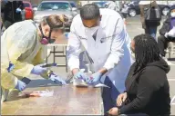  ?? Matthew Brown / Hearst Connecticu­t Media ?? Dr. Fawad Hameedi of DOCS Urgent Care Stamford administer­s a COVID-19 nasal swab test on Lakeisha Thompson, 34, of Stamford, at a walk-up testing site for the coronaviru­s at AME Bethel Church in Stamford on May 2.