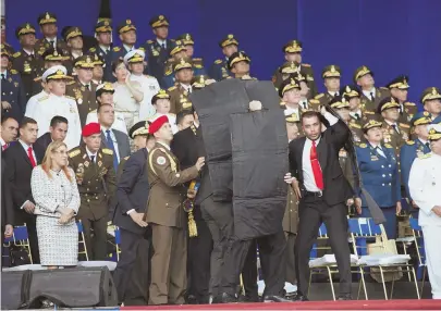  ?? PHOTO BY XINHUA VIA AP ?? ‘PROBLEMATI­C’: In this photo released by China’s Xinhua News Agency, security personnel surround Venezuela’s President Nicolas Maduro during a failed assassinat­ion attempt by drone Saturday.