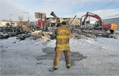  ?? JOHN LUCAS/ EDMONTON JOURNAL ?? A firefighte­r watches an excavator clear debris Friday after an overnight blaze destroyed two south-side businesses.