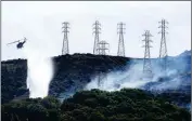  ?? ASSOCIATED PRESS ?? A HELICOPTER DROPS WATER near power lines and electrical towers while working at a fire on San Bruno Mountain near Brisbane, Calif. California’s Pacific Gas & Electric is faced regularly with a no-win choice between risking the start of a deadly wildfire or immiserati­ng millions of paying customers by shutting off the power.