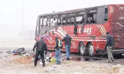  ?? JOE RONDONE/THE COMMERCIAL APPEAL ?? Law enforcemen­t officers inspect the site where a tour bus carrying passengers overturned just after midday Wednesday in Desoto County, Miss. The crash came as a winter storm has been raking parts of the South.