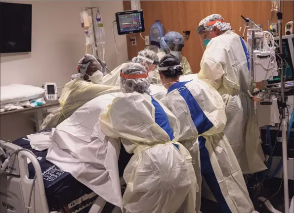  ?? John Moore / Getty Images ?? A “prone team,” wearing personal protective equipment, turns a COVID-19 patient onto his stomach in a Stamford Hospital intensive care unit on April 24, 2020.