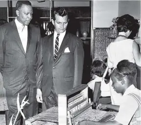  ?? FILE ?? A member of the staff of Things Jamaican, demonstrat­es the working of a straw weaving machine while then Senator, the late Hon. Hugh Shearer (left) and Edward Seaga, then minister of developmen­t and welfare watch. This was at the presentati­oin of Christmas designs by Craft Developmen­t Agency at Things Jamaican, 114 Kings Street on November 28, 1966.