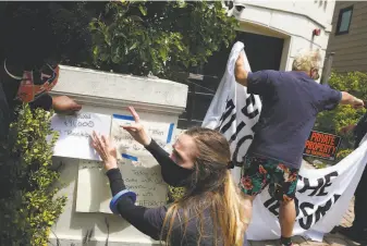  ?? Lea Suzuki / The Chronicle ?? Minister Cherri Murphy (left), and Lauren Casey (second from left), organizers with Gig Workers Rising, post “grievance notes” at Uber CEO Dara Khosrowsha­hi’s San Francisco home during a driver caravan protest in June.