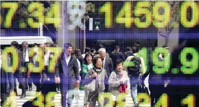  ??  ?? TOKYO: People are reflected on an electronic stock indicator of a securities firm in Tokyo. — AP